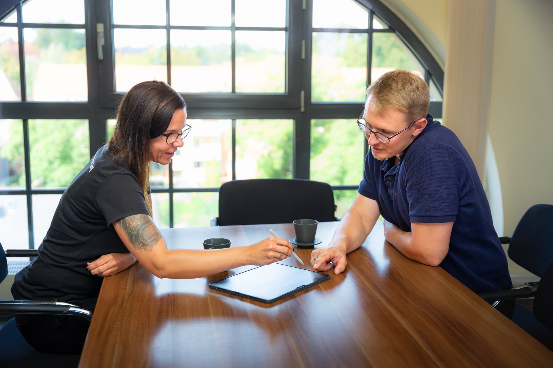Zwei Kolleginnen und Kollegen besprechen Pläne am Tisch im Büro